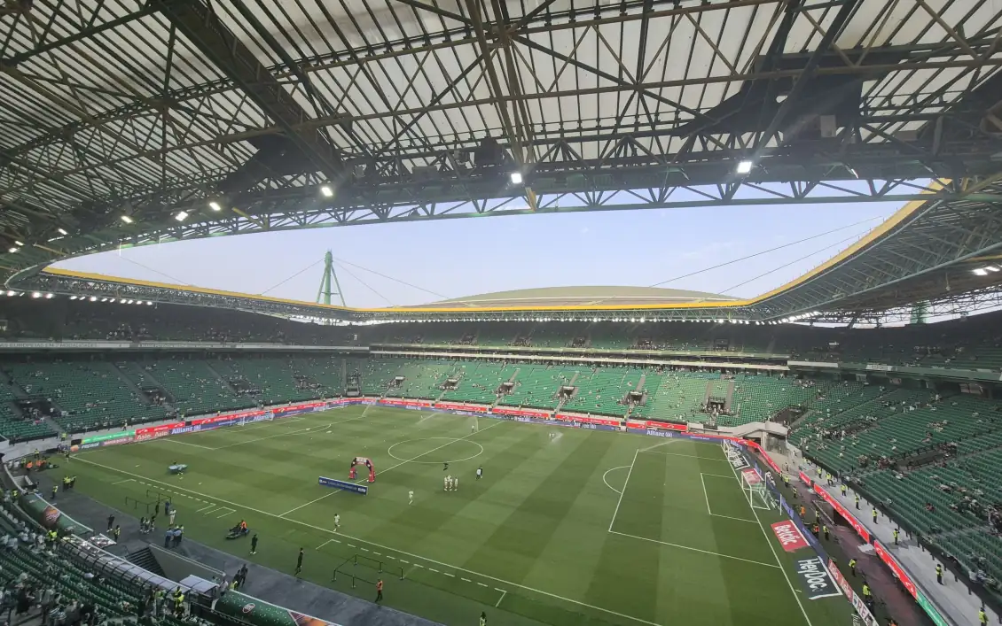 Interior do Estádio José Alvalade antes de um jogo, com as equipas a aquecer no relvado e as bancadas verdes a encher