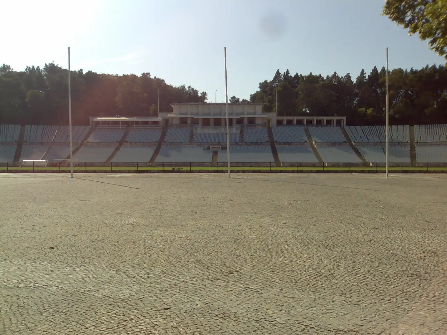 Tribuna de honra do Estádio Nacional, no Jamor, com a colunata branca e as bancadas vazias vistas do largo empedrado